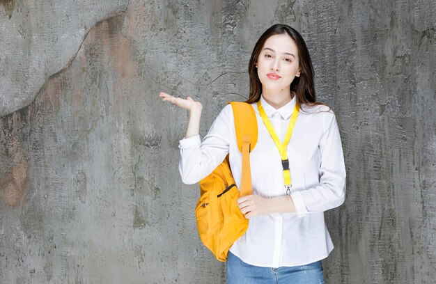 Young woman with backpack holding open space. High quality photo