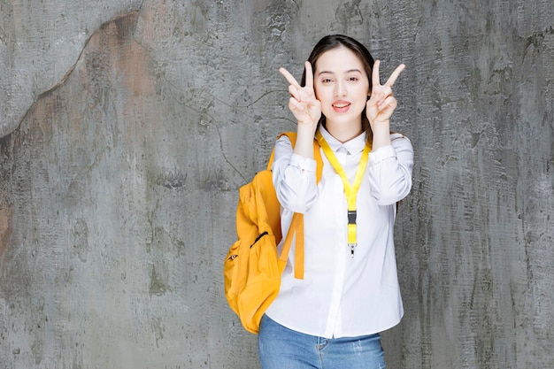 Young woman with backpack showing victory sign. High quality photo