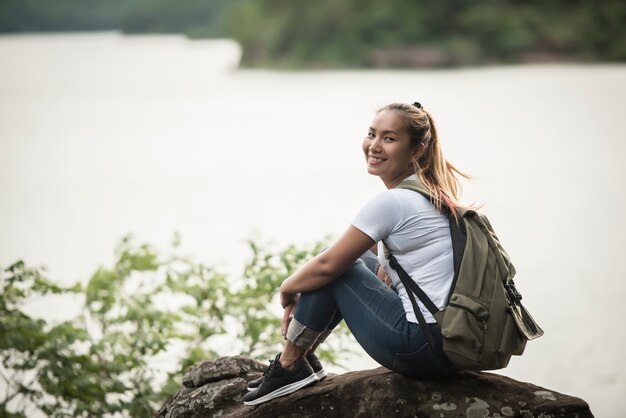 バックパックを着た若い女性は森と一緒に楽しむ。旅行のコンセプト。