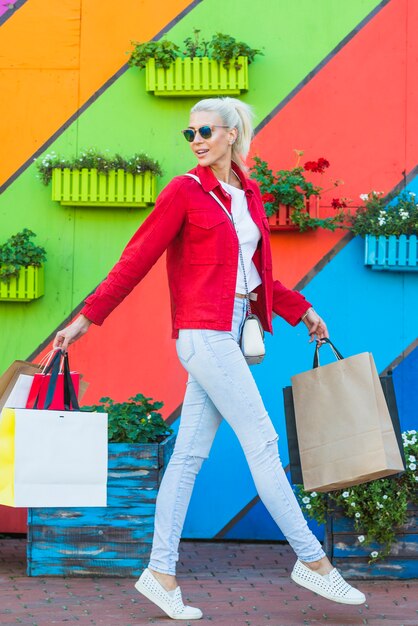 Young woman with bags near colourful wall