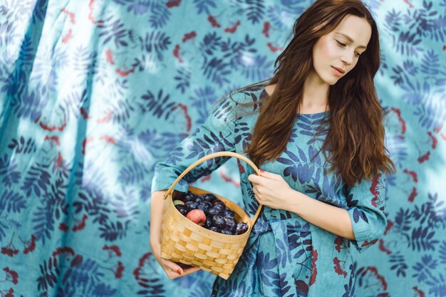 young woman with a basket of fruits, plums and apples.