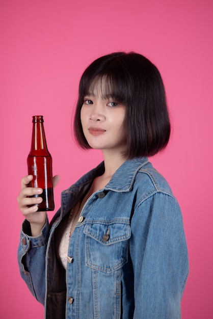 Young woman with beer bottle beer on pink 