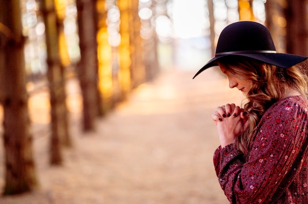 Foto gratuita giovane donna con cappello nero in preghiera