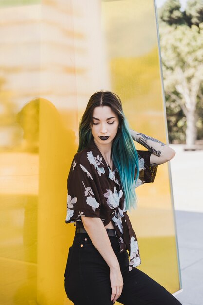 Young woman with black lipstick posing in front of yellow backdrop