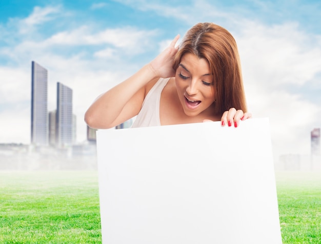 Young woman with blank board over cityscape