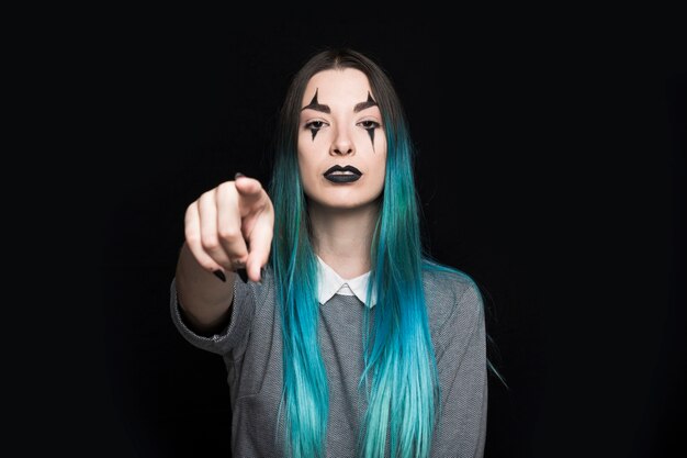 Young woman with blue hair and dark make up posing in studio