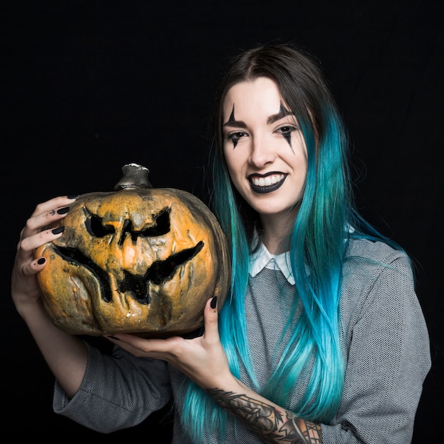 Young woman with blue hair holding pumpkin