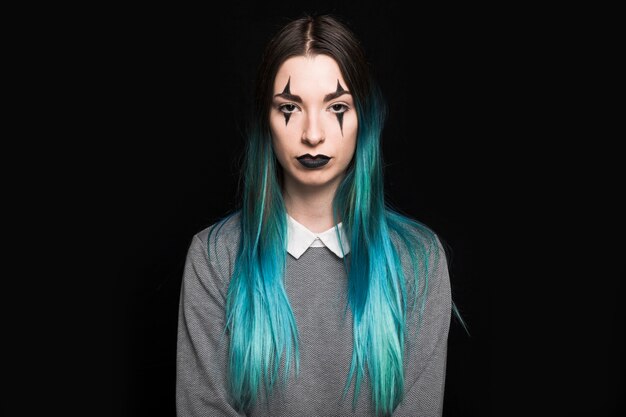 Young woman with blue hair and makeup standing in studio