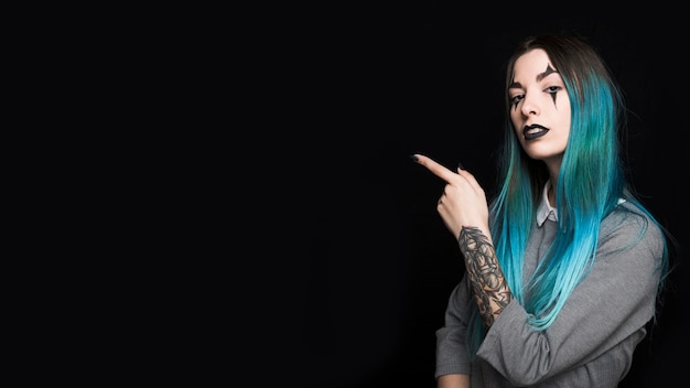 Young woman with blue hair pointing with finger aside