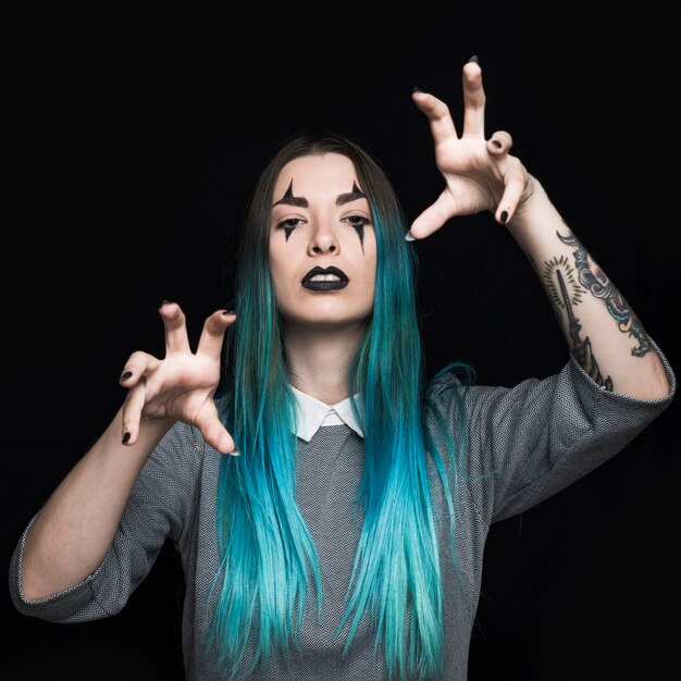 Young woman with blue hair and tattoo posing in studio