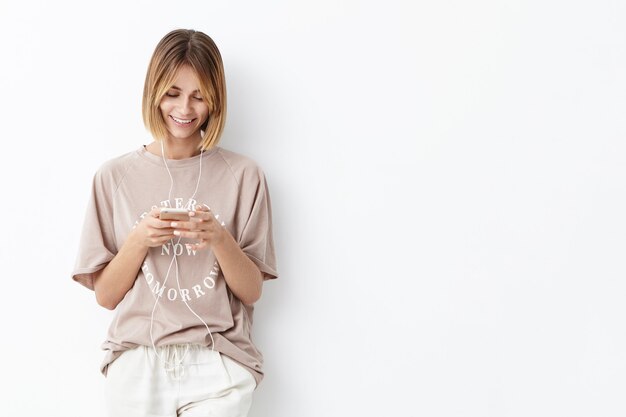 Young woman with bobbed hair wearing casual clothes listening to music