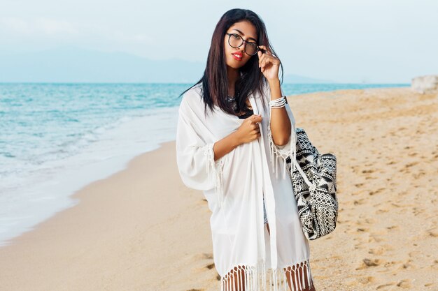 Young woman with boho bag posing on tropical beach