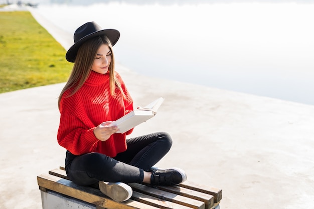 Giovane donna con libro sulla panchina