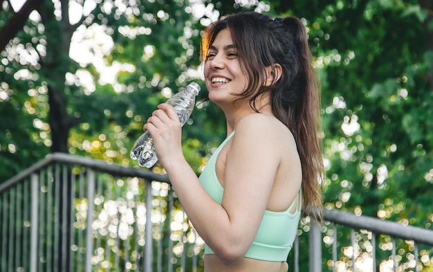 Foto gratuita una giovane donna con una bottiglia d'acqua in allenamento allo stadio