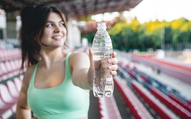 スタジアムでのトレーニングで水のボトルを持つ若い女性