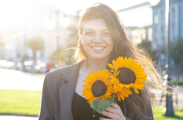 해질녘 햇살 아래 해바라기 꽃다발을 들고 있는 젊은 여성