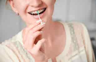 Free photo young woman with braces on teeth using elastic cleaning toothpick