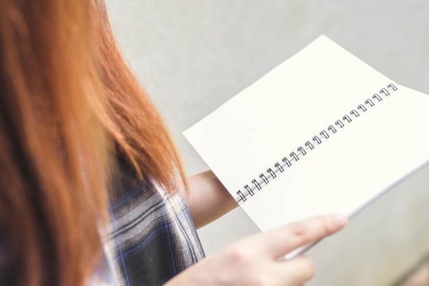 Young woman with brown hair reading book, hands holding opened book, Vintage effect style pictures.