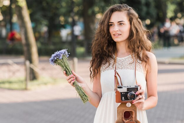 Young woman with camera and flowers