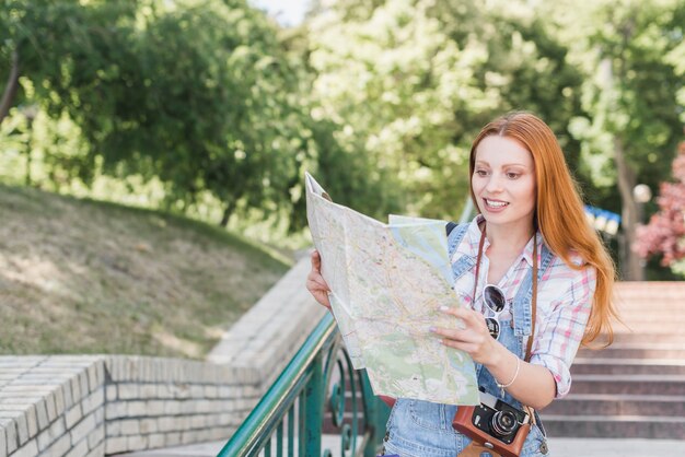 Young woman with camera reading map
