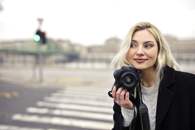 Giovane donna con una macchina fotografica in strada