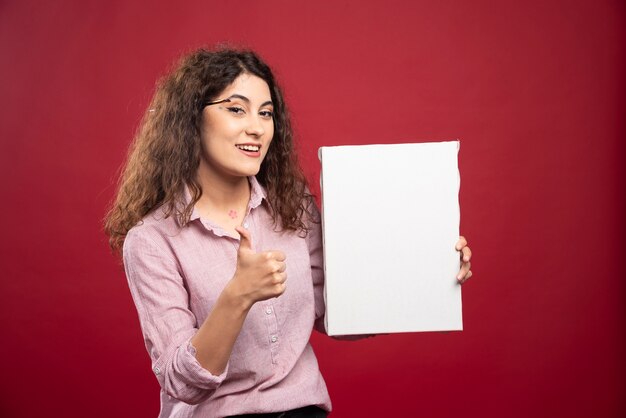 Young woman with canvas giving thumbs up