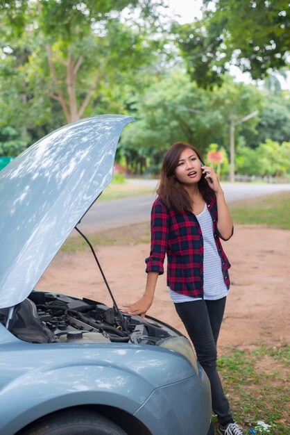 若い女性が車を壊し、彼女は緊急サービスを呼んでいます。