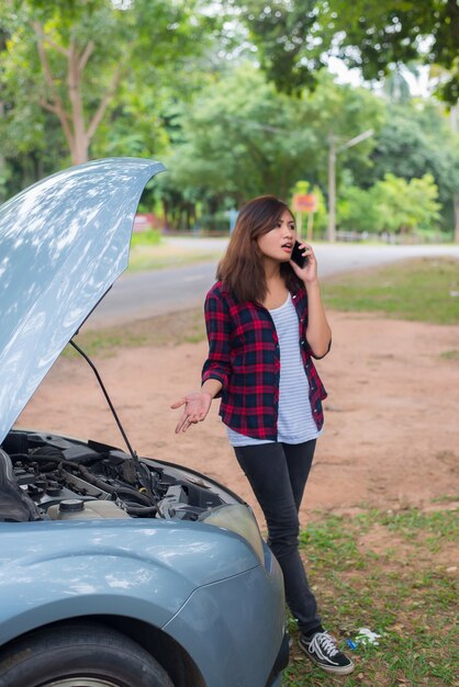 Young woman with car breaks down and she is calling the emergency services.