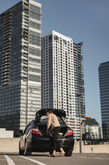 Foto gratuita giovane donna con un'auto nel parcheggio