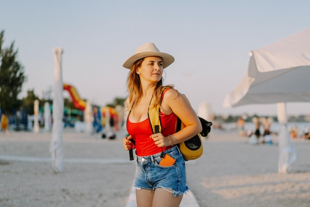 young woman with a cat in a backpack on the seashore. Travel concept with a pet. Cat in the backpack with porthole.