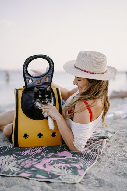 해변에 배낭에 고양이와 함께 아름 다운 젊은 여자. 애완 동물과 함께 여행 개념입니다.