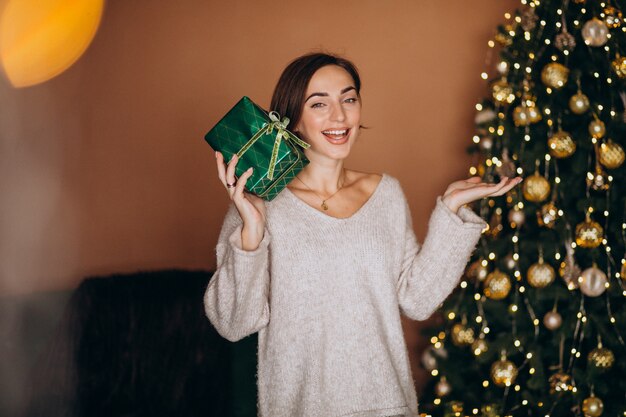 クリスマスツリーがクリスマスプレゼントを持つ若い女性