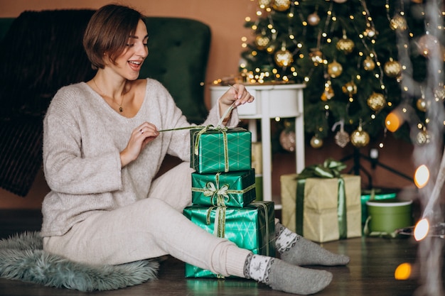 クリスマスツリーがクリスマスプレゼントを持つ若い女性