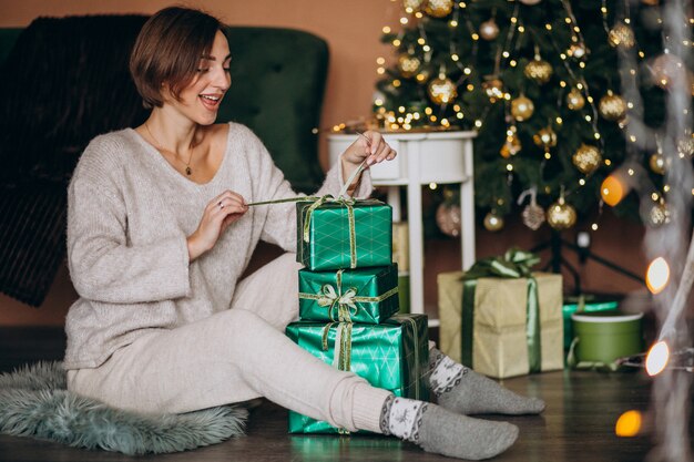 Молодая женщина с рождественским подарком у елки