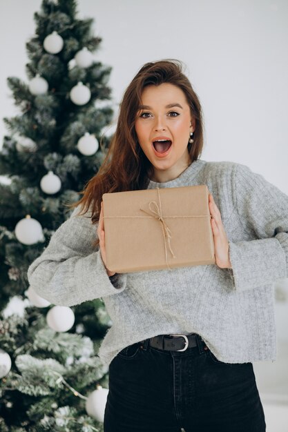 Young woman with christmas presents by the christmas tree