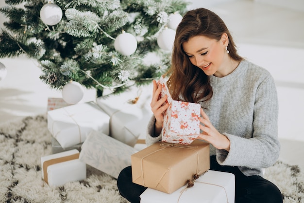 クリスマスツリーでクリスマスプレゼントと若い女性