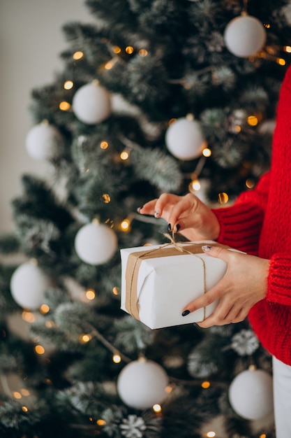 クリスマスツリーでクリスマスプレゼントと若い女性