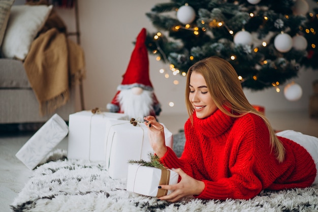 クリスマスツリーでクリスマスプレゼントと若い女性