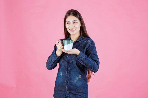 Молодая женщина с чашкой кофе улыбается и чувствует себя позитивно