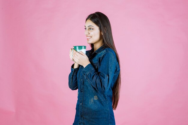 笑顔と前向きな気持ちのコーヒーカップを持つ若い女性