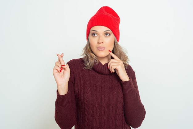 Young woman with crossed fingers looking aside