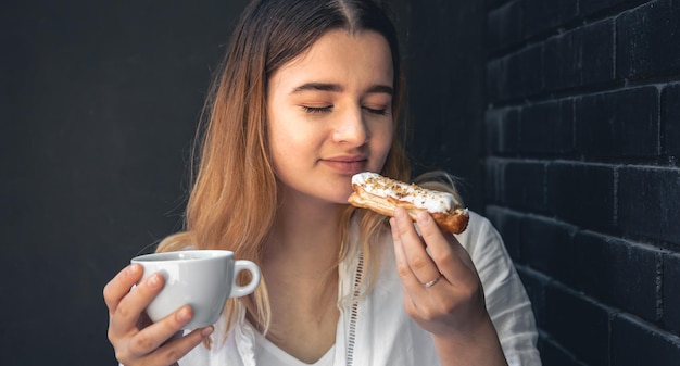 Una giovane donna con una tazza di caffè e un bignè in mano