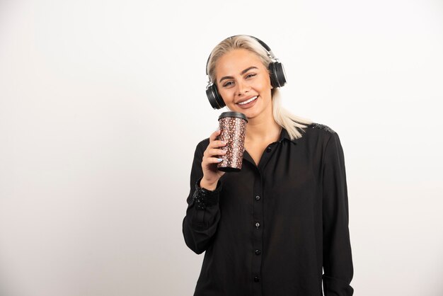 Young woman with cup in headphones on a red background. High quality photo