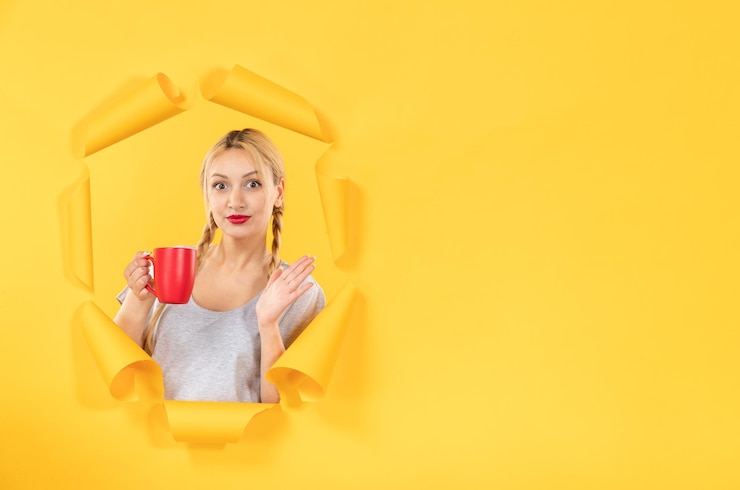 Бесплатный Фотография молодая женщина с чашкой чая на фоне порванной желтой бумаги делает покупки для лица