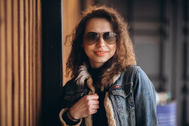 Giovane donna con i capelli ricci in giacca di jeans