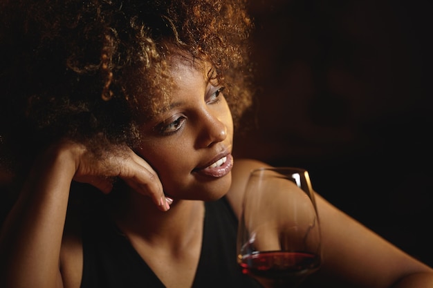 Young woman with curly hair and a glass of red wine