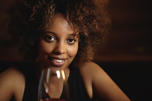 Young woman with curly hair and a glass of red wine