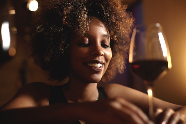 Young woman with curly hair and a glass of red wine