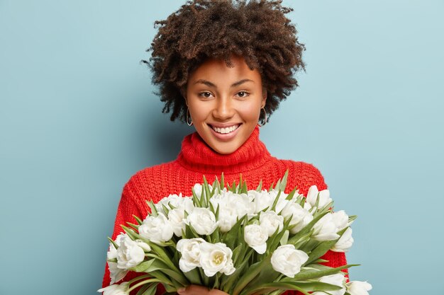 白い花の花束を保持している巻き毛の若い女性