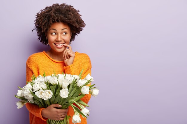 Young woman with curly hair holding bouquet of white flowers